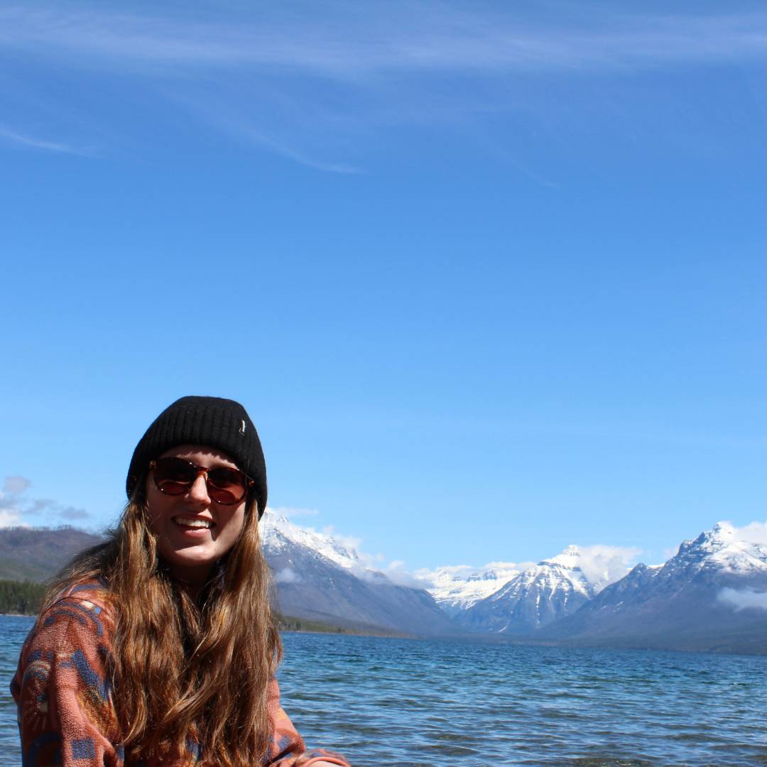 Girl wearing sunglasses and smiling with mountains in the background